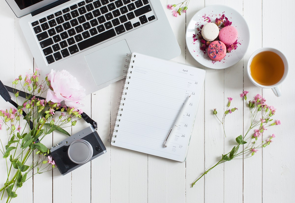 Birds-eye view picture of laptop on table surrounded with items